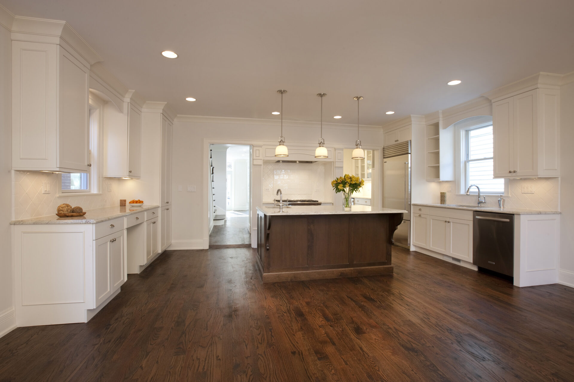 Spacious kitchen space with wooden flooring and white walls and features